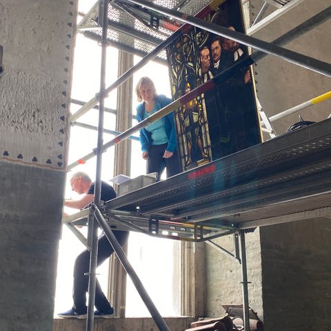 Die Restauratoren stehen auf einem Gerüst im Ulmer Münster und arbeiten an der Aufhängung für die Bleiglasfenster in der Christuskammer.